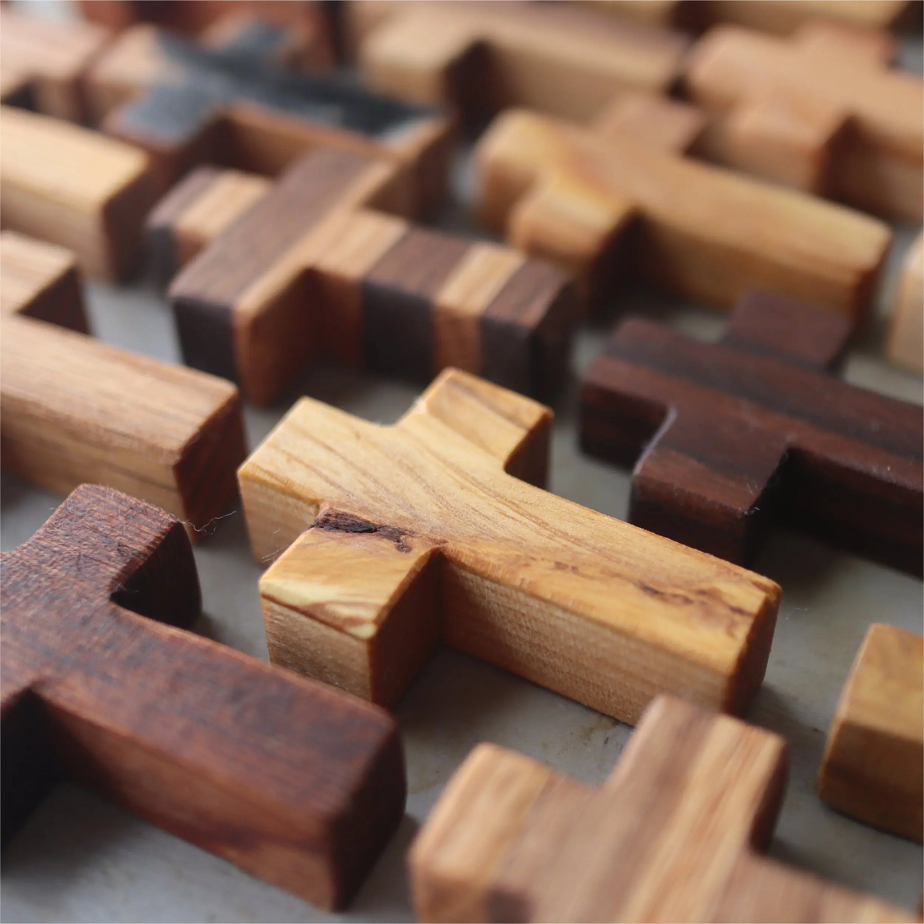 Collection of handmade wooden pocket crosses in various wood tones.