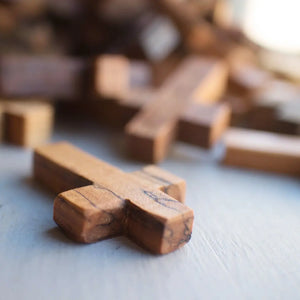 Wooden pocket crosses on a light gray surface with a shallow depth of field.