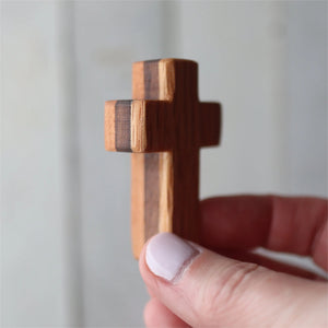 Handheld wooden pocket cross made of contrasting wood pieces.