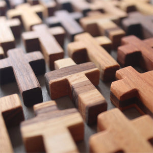 Row of small wooden pocket crosses in various wood tones.