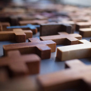 Scattered wooden pocket crosses in various shades of brown and tan.