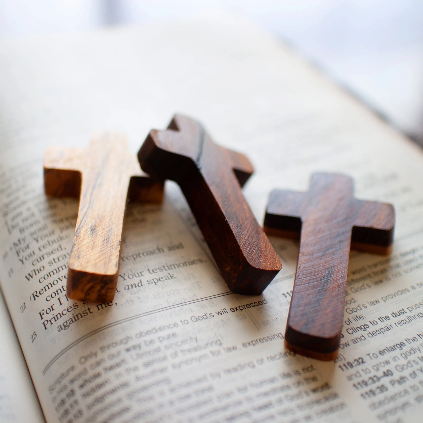 Three wooden crosses on an open Bible.