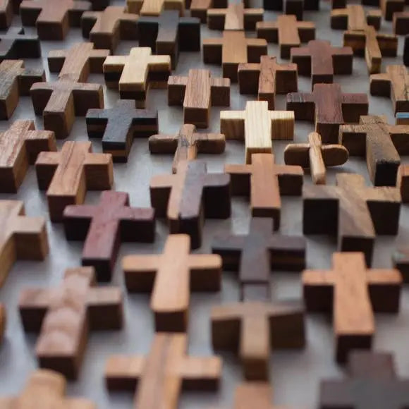 A close-up view of many small, light brown and dark brown wooden crosses.