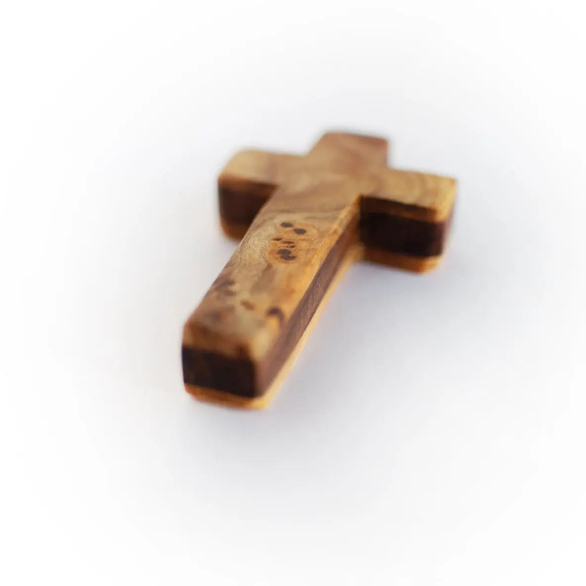 Close-up of a small wooden cross with distinct wood grain patterns.