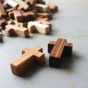 Several handmade wooden crosses on a textured grey surface, two in foreground.