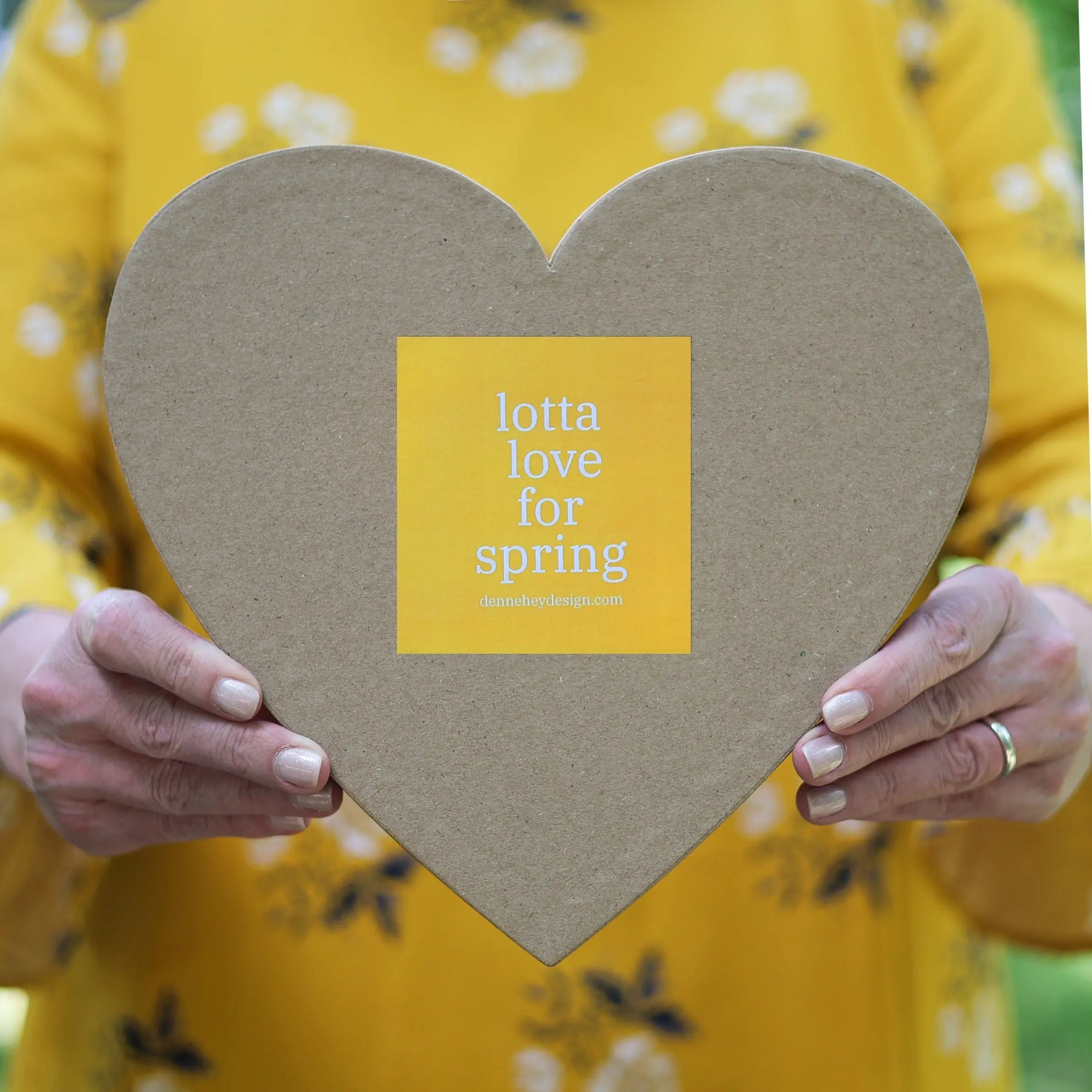 Heart-shaped box with a yellow sticker featuring white text.