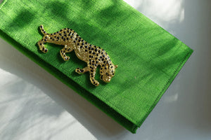 Gold jaguar brooch on an emerald green clutch