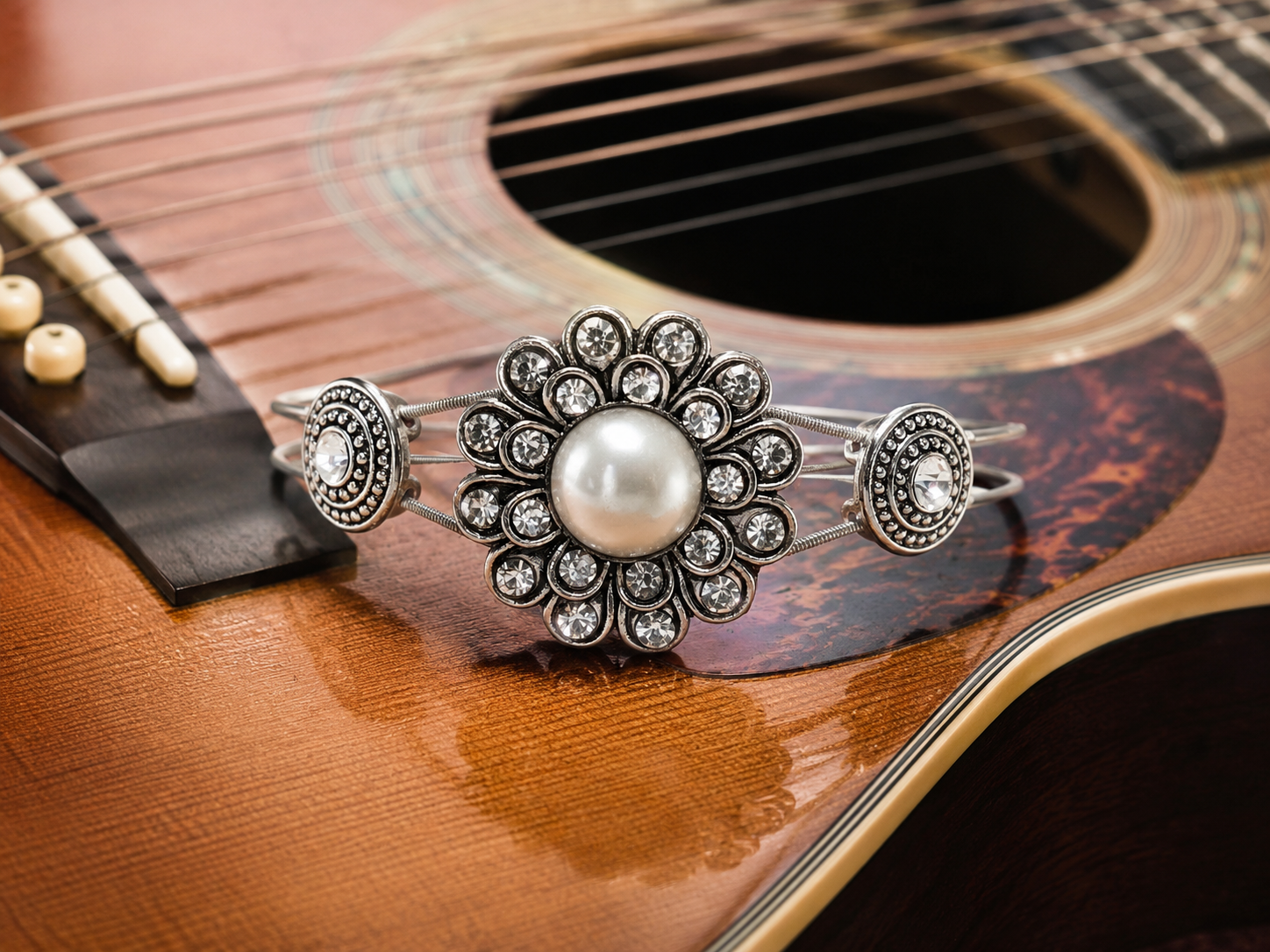 Silver bracelet with a pearl on an acoustic guitar