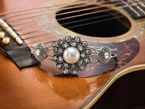 Silver bracelet with a pearl on an acoustic guitar