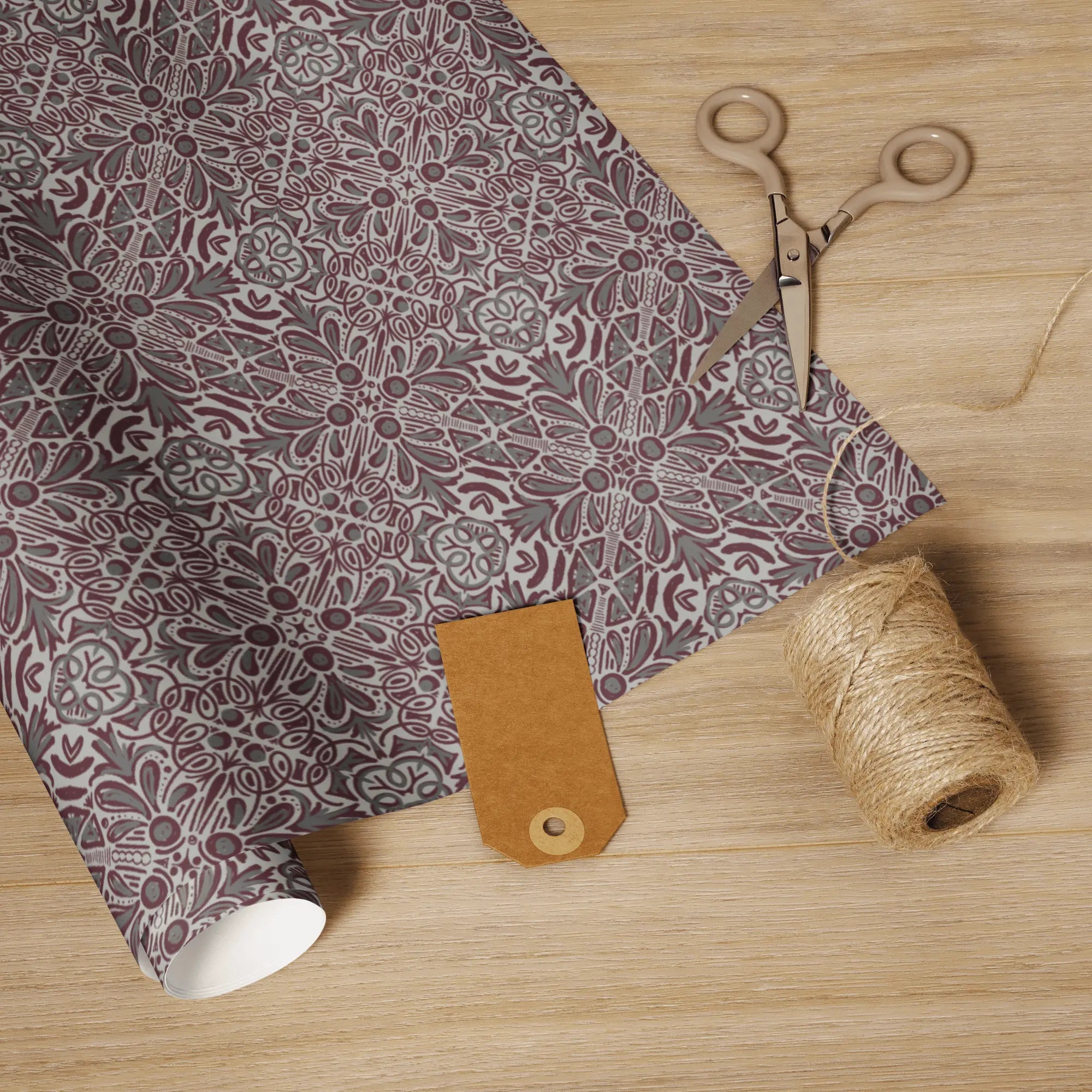 Jubilee maroon and grays wrapping paper, featuring scissors, string, and a gift tag on a wooden surface.