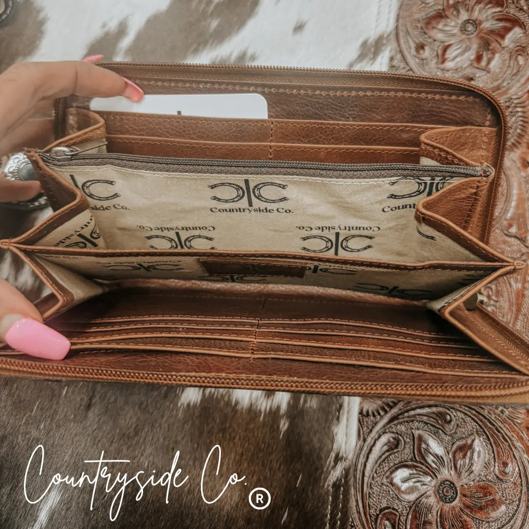 Brown tooled leather wallet with multiple card slots and zipper closure.