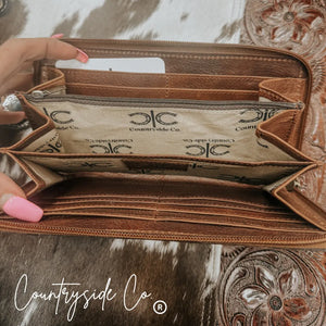 Brown tooled leather wallet with multiple card slots and zipper closure.
