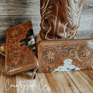 Brown tooled leather wallet with white and black cowhide and floral detail.