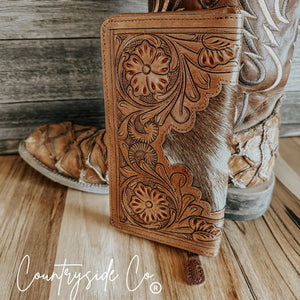 Brown tooled leather wallet with cowhide accents and floral embossing.