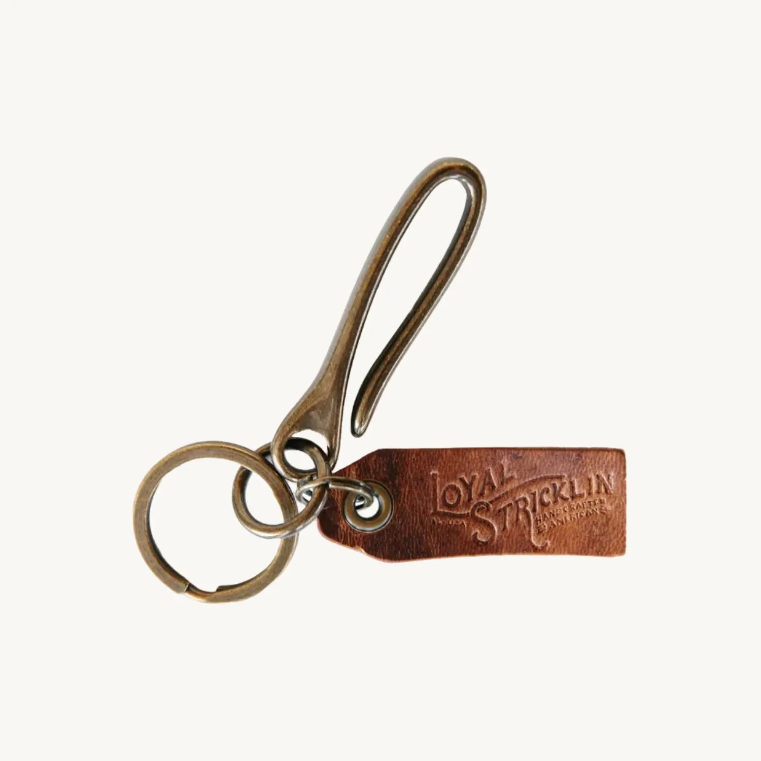 Antique brass keychain with fish hook clasp, key ring, and leather tag stamped \"Loyal Stricklin\"