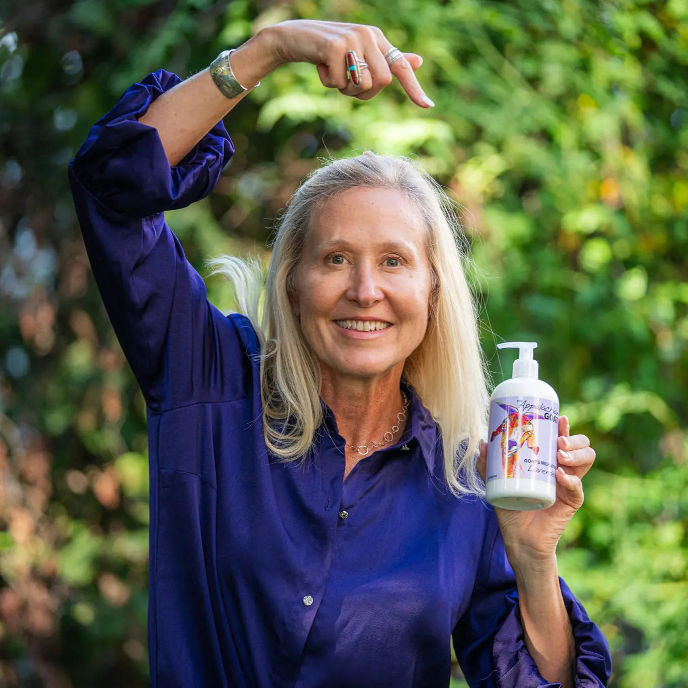 Woman holding lavender goat's milk lotion bottle outdoors