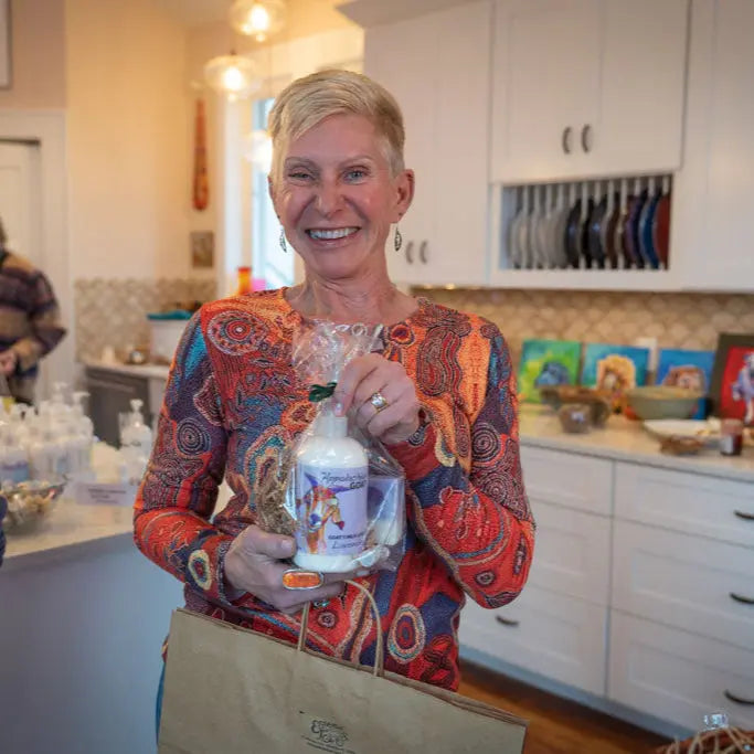 Woman holding a bottle of LAVENDER GOATS MILK LOTION from Main Street Collective