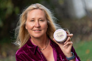 Woman holding a round lavender thyme arnica soufflé jar by Essential Journeys