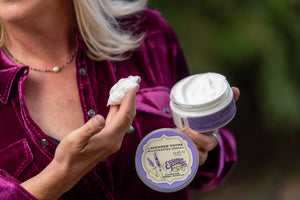Woman holding lavender thyme arnica soufflé jar and dollop of cream by Essential Journeys.
