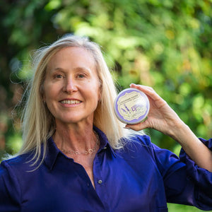 Woman holding a tin of Lavender Thyme Wildcrafted Arnica Herbal Souffle.