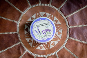 Lavender Thyme Arnica Soufflé with lavender sprigs on a patterned leather surface.