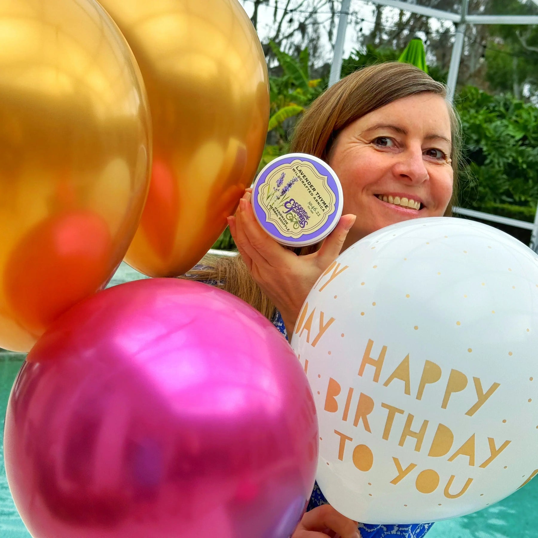 Lavender Thyme Arnica Souffle held by woman with birthday balloons.