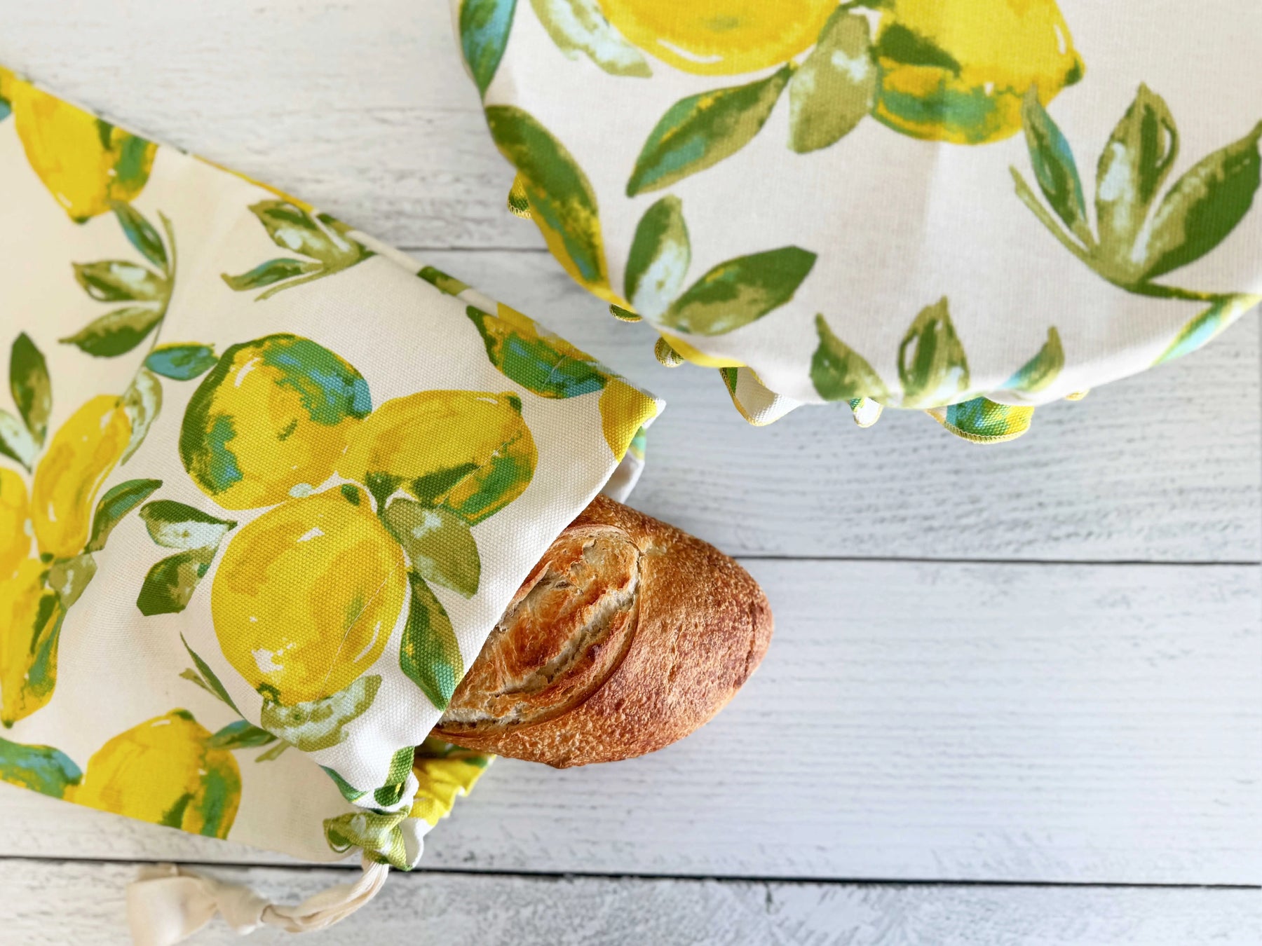 Bread bag with lemon print and a loaf of bread next to a bread cover.