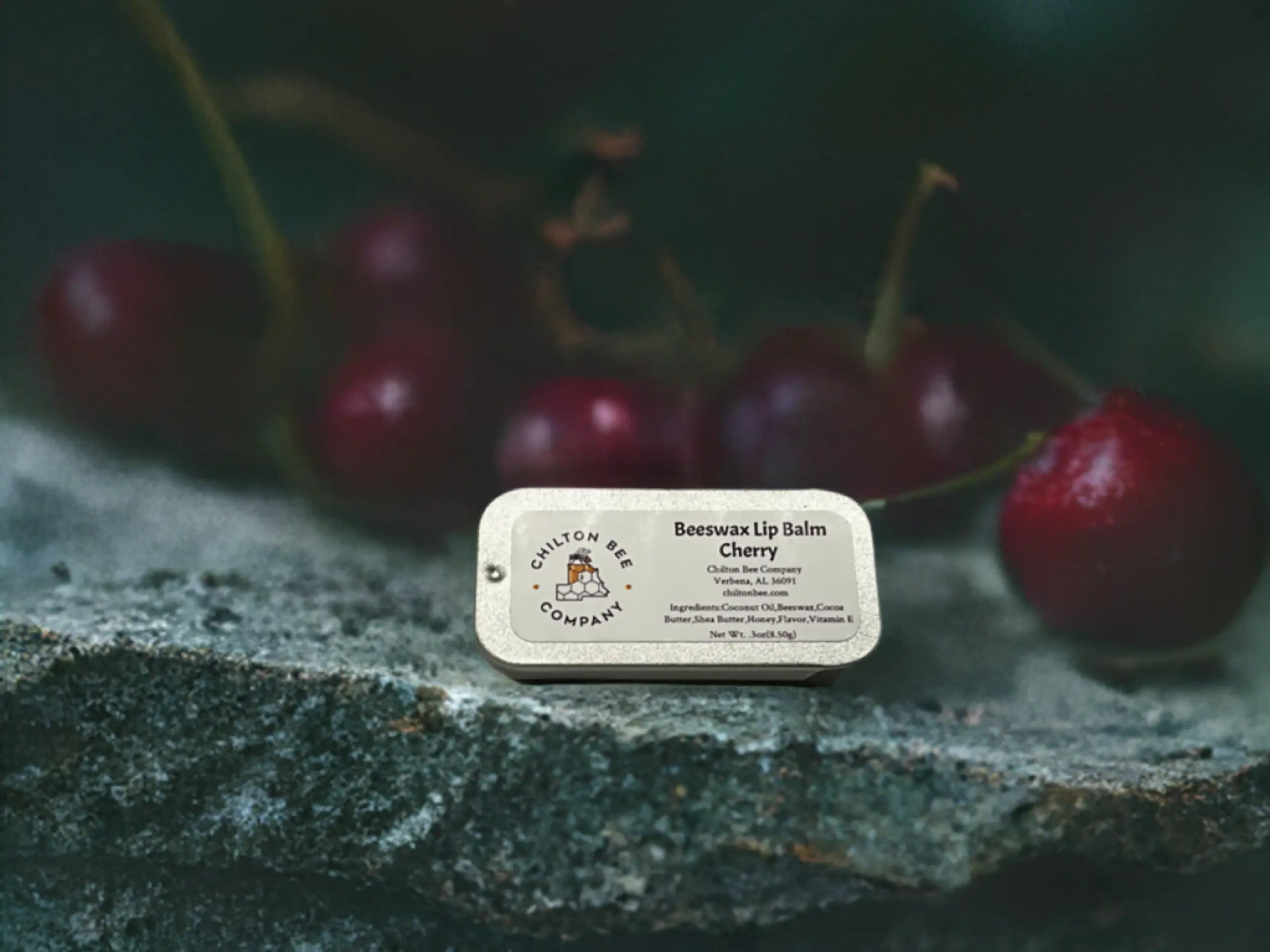 Chilton Bee Company Beeswax Lip Balm in Cherry flavor, presented in a small tin with a cherry background.