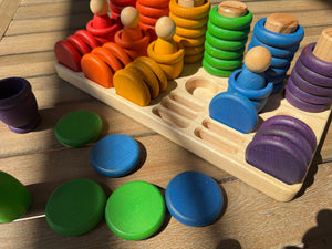 Wooden sorting tray with colorful rainbow stacking toys and loose discs.