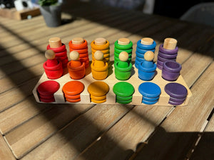 Wooden sorting tray with colorful stacking pegs and discs.