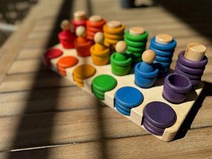 Wooden sorting tray with rainbow colored stacked pieces and peg people.