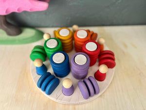 Wooden sorting tray with rainbow colored stacking pieces and wooden pegs.