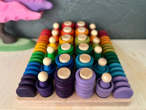 Wooden rainbow stacking toys arranged on a light-colored wooden tray.