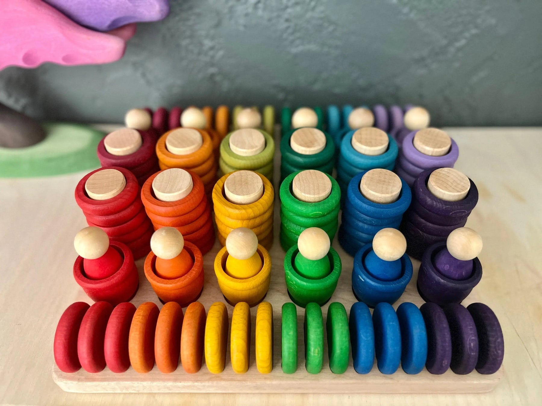 Maple sorting tray filled with colorful wooden stacking toys and rings.
