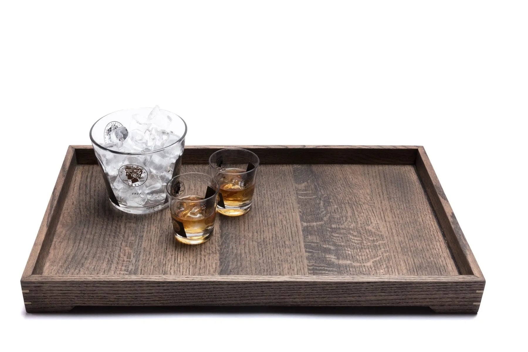 Wooden tray holding two glasses with liquor and ice bucket with ice cubes.