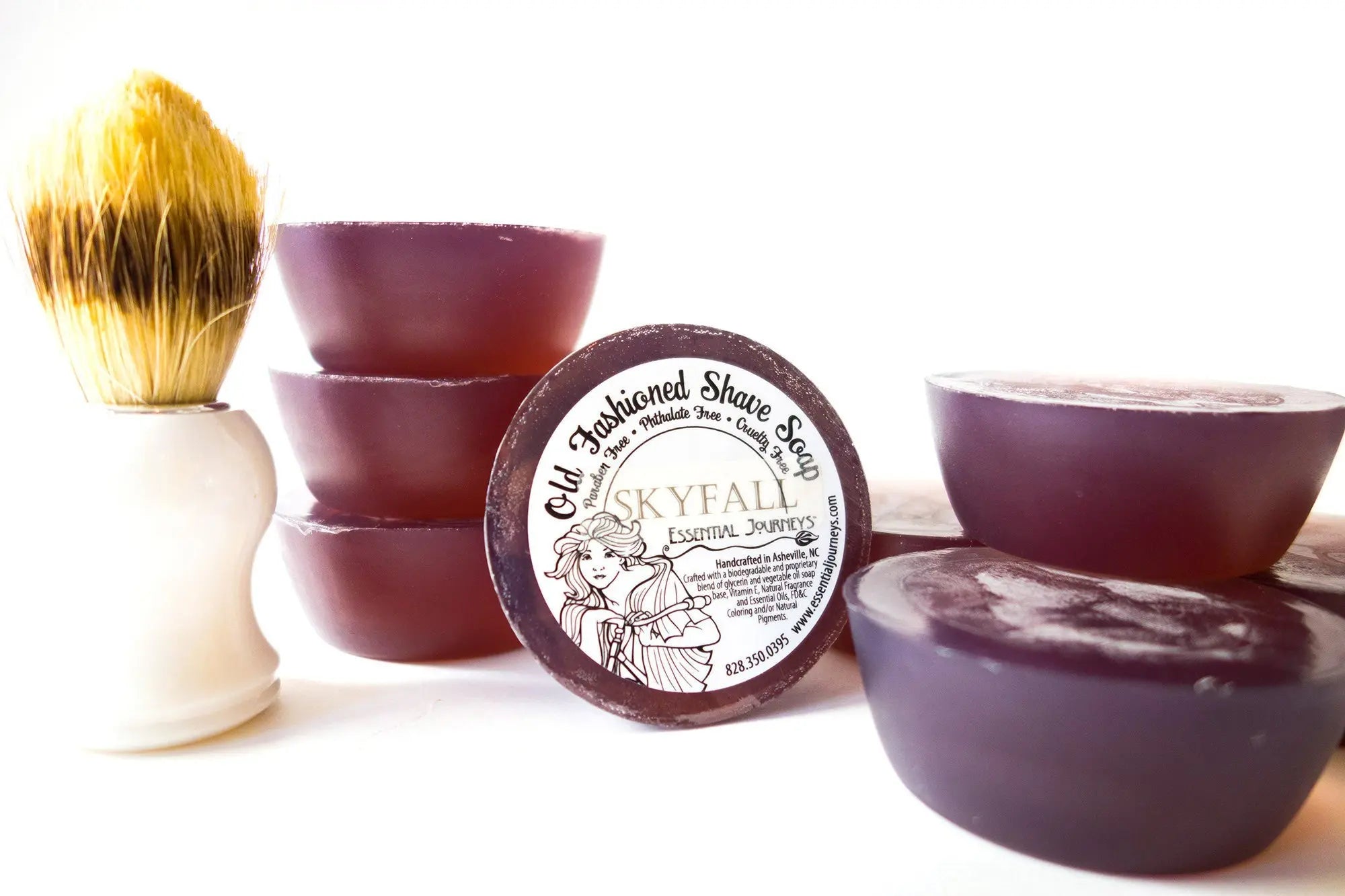 Purple round shave soap bars and a white handle brush with yellow and brown bristles.