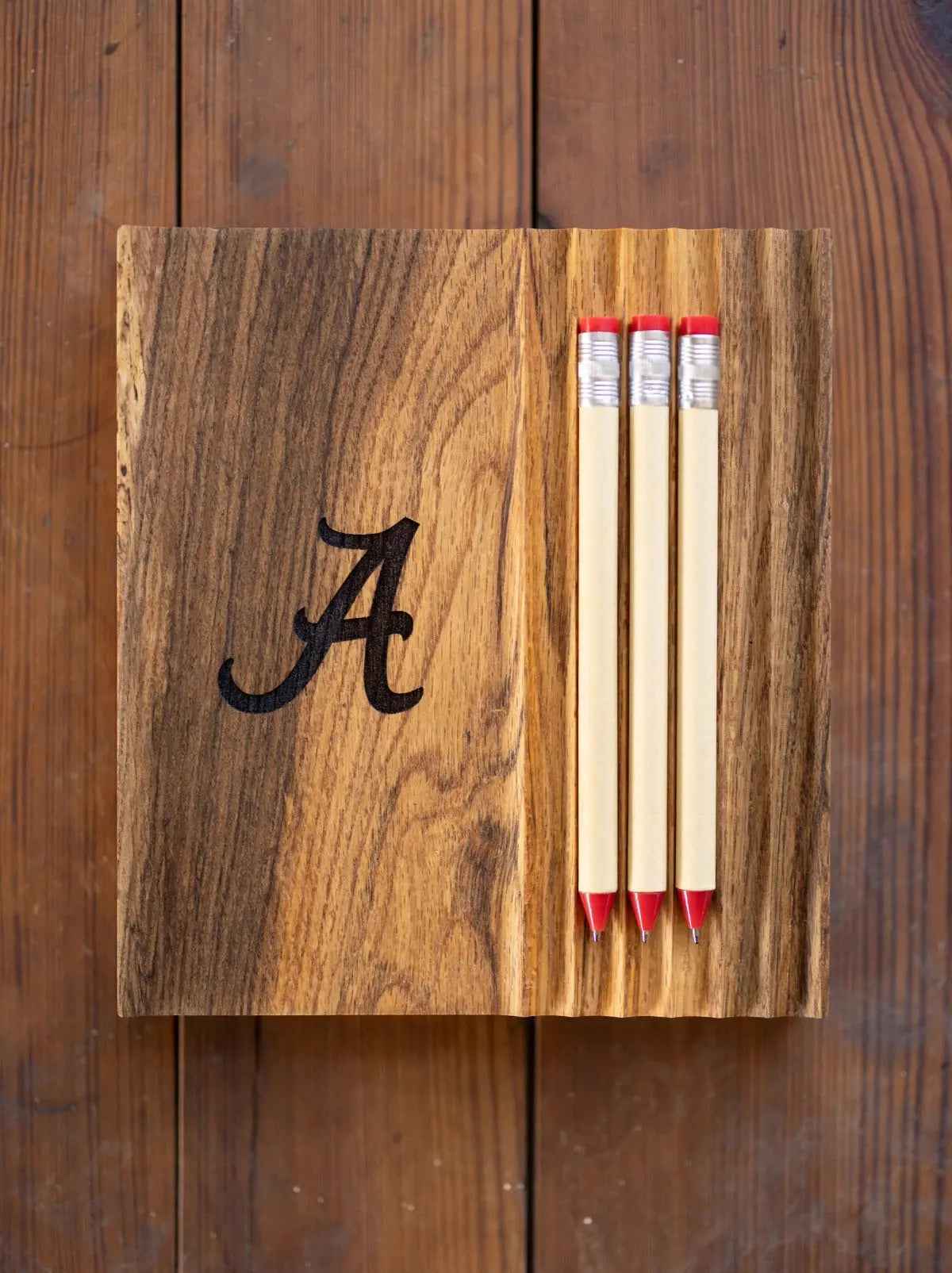 Wooden tray with the letter A and three pencils with red erasers.