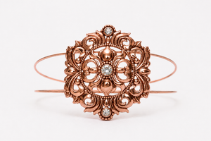 Rose gold bracelet with intricate design and diamond accents on a white background