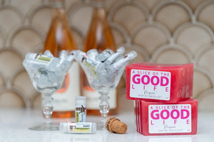 Prosecco lip butter with soap bars and rose wine bottles in the background.