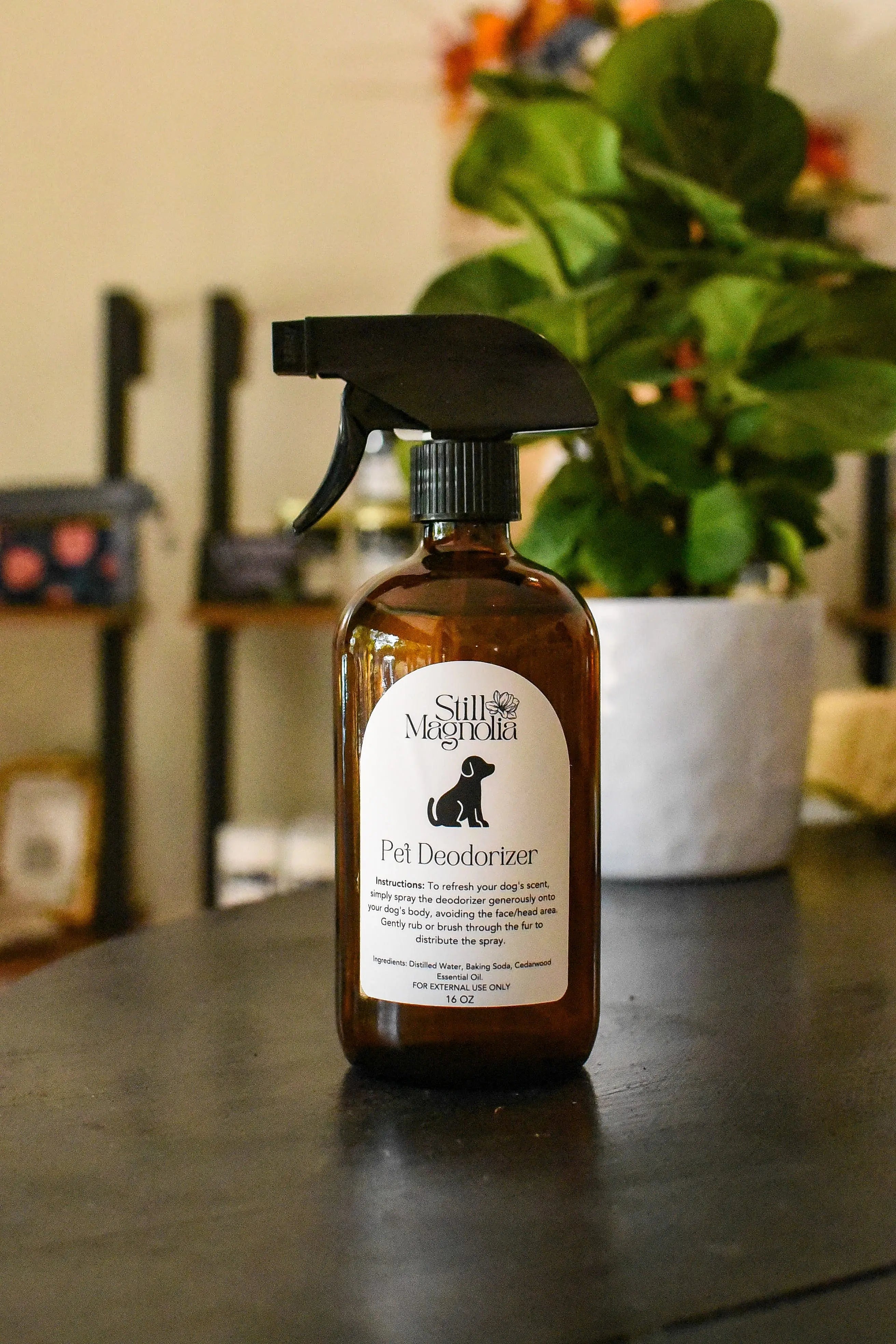 Amber glass spray bottle of Still Magnolia Pet Deodorizer with dog silhouette label.