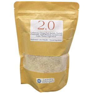 Brown bag of 2.0 scented HE laundry detergent by Main Street Collective, with ingredient list and transparent window showing product.