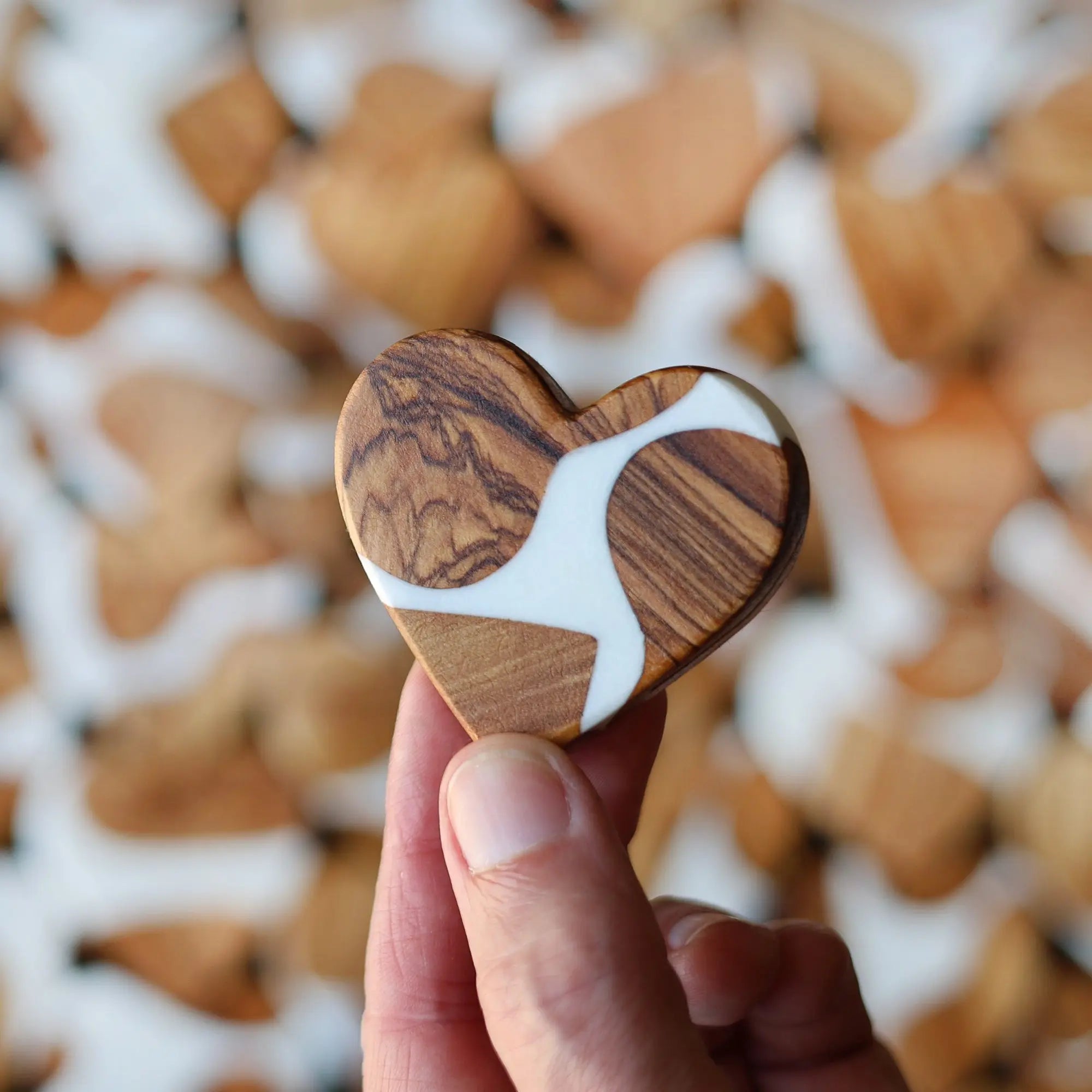 Heart-shaped wooden and white resin craft held in hand