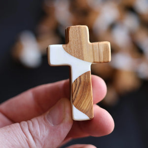 Pocket cross made of reclaimed olive wood and white resin with unique grain patterns.