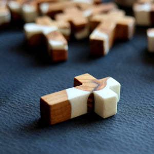 Wooden and white resin cross on a dark textured surface.