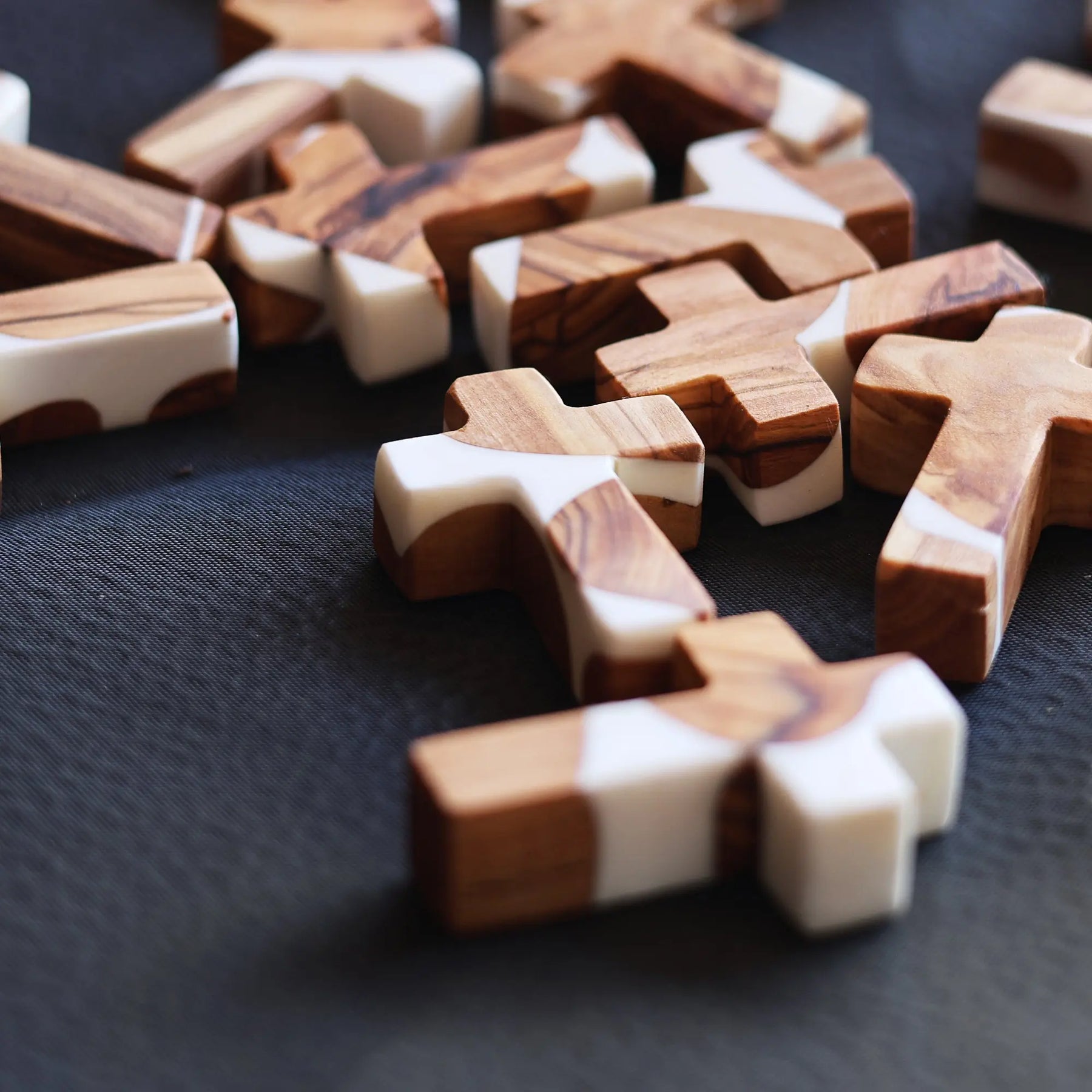Wooden and white resin cross pieces scattered on a dark surface.