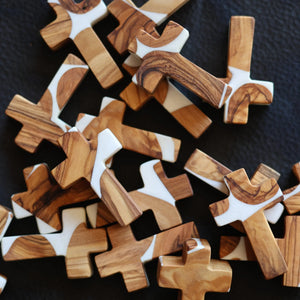 Olive wood and white resin pocket crosses with natural grain patterns.