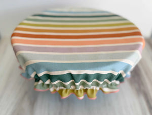 Reusable cotton bowl cover with beach chair stripes and ruffled edge.