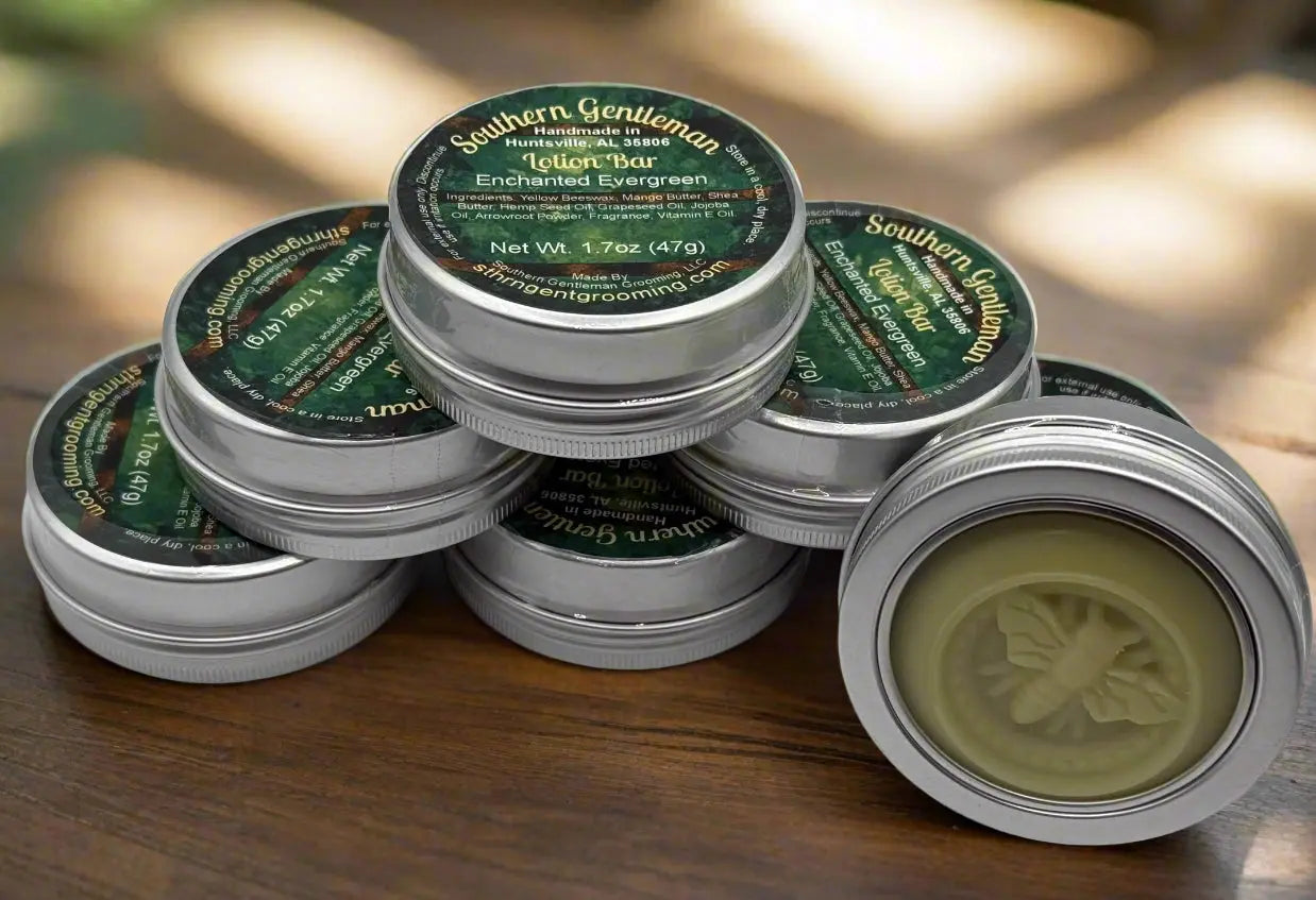 Stack of Southern Gentleman Lotion Bars in silver tins with green labels, one open showing the bar's bee imprint.