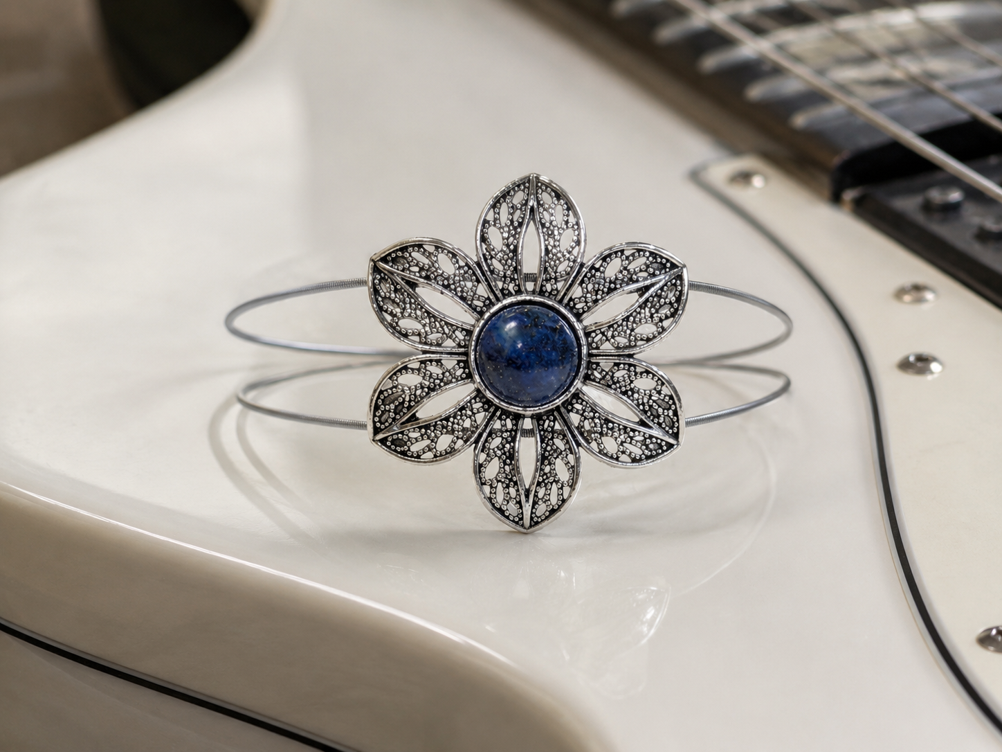Silver flower-shaped brooch with a blue gemstone on a white surface