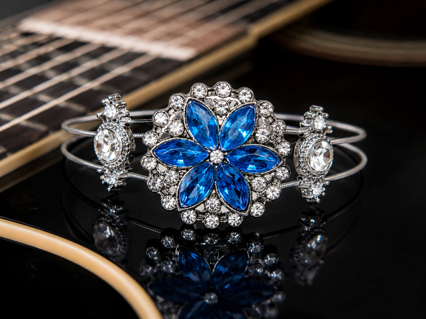 Bracelet with blue flower design and clear stones on a guitar